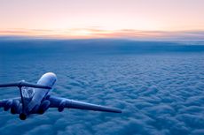 An airplane at sunrise flying over the clouds, away from the camera