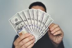 Man holds a stack of $100 bills.