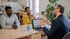 A husband and wife sit at their dining room table talking with a financial adviser.