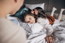 Three people, husband and wife together in hotel room on bed with their little daughter, they are on vacation.