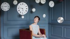 A woman looks at a clock.