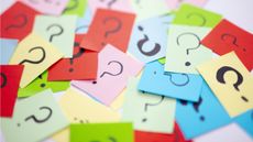 Question marks written on sticky notes are scattered across a table.