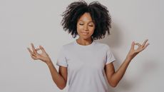 A young woman looks calm as she strikes a Zen pose.