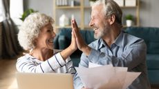 Senior couple giving high five. Man is holding financial documents.