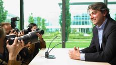 Man sitting at a desk being photographed at a conference