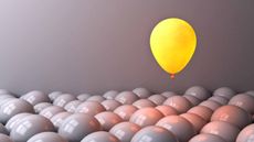 Yellow balloon floating above lots of gray balloons